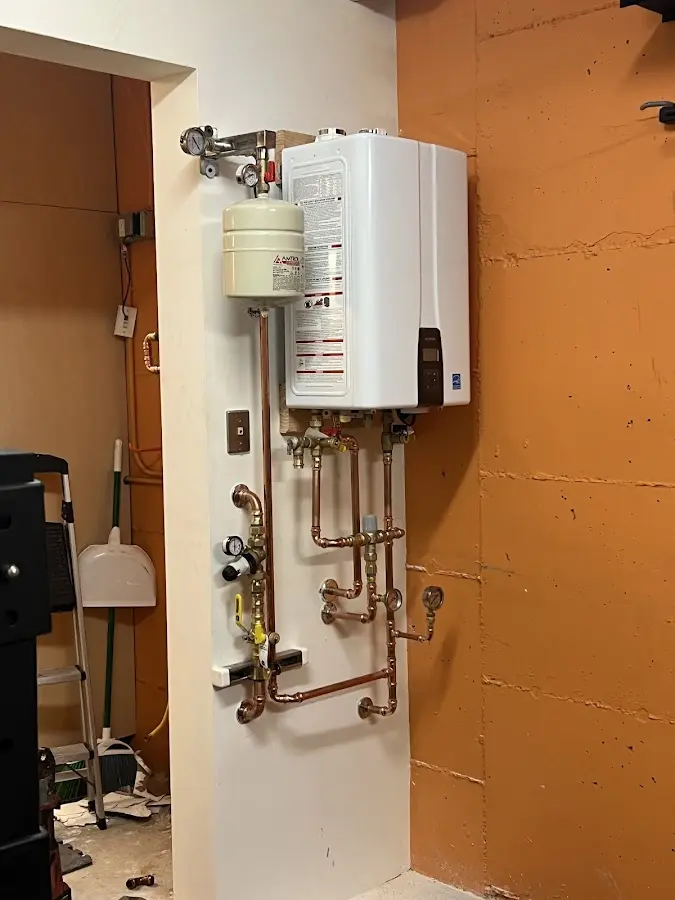 Plumbing technician inspecting water heater connections in Orrington
